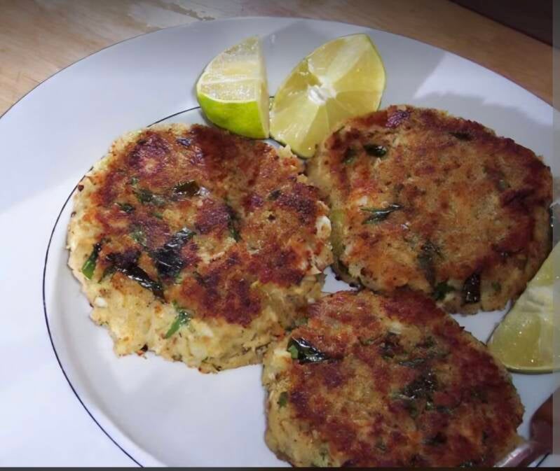 Golden brown Cajun garfish patties fried crisp with green herbs served on white plate with lime wedges, Grandma Laura’s recipe from Manchac Louisiana, @NanaTeesCajunHome