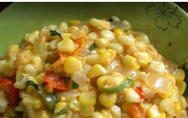 Close-up of creamy Cajun Corn Maque Choux in green floral bowl with fresh corn kernels, bell pepper, tomato, onion and green onion in rich sauce, Louisiana summer side dish recipe, @NanaTeesCajunHome
