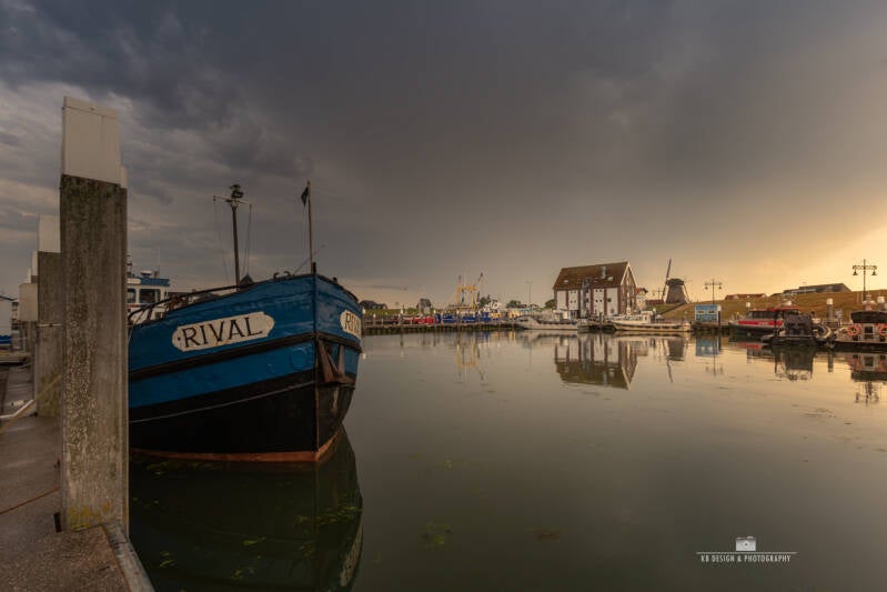 Oudeschild haven bij zonsondergang met dreigende lucht
