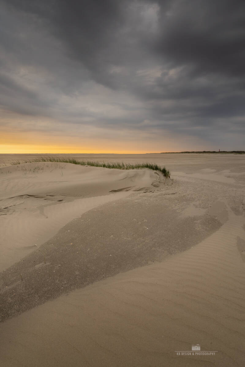 Dreigende wolken boven het strand van Schiermonnikoog met de vuurtoren in de verte
