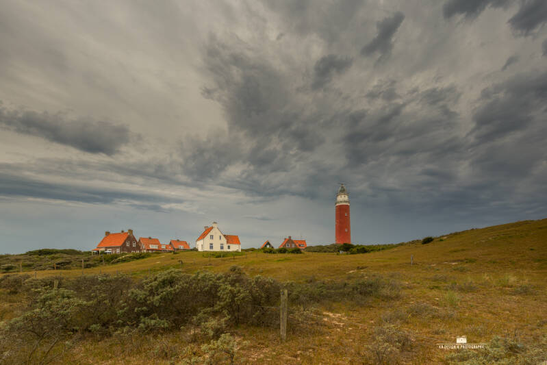 De karakteristieke vuurtoren van Texel staat fier boven het duinlandschap, terwijl een indrukwekkend en dreigend wolkendek zich boven het eiland samenpakt