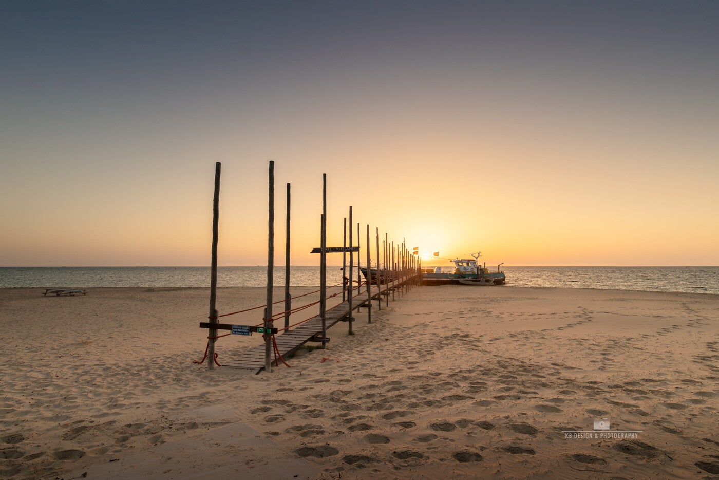 Kleurrijke zonsopgang bij de steiger van Waddenveer de Vriendsch op het strand van Texel, een uitnodigend gezicht.