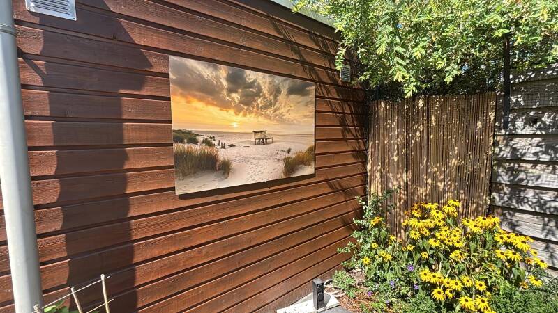 Een foto van het strand van Ameland afgedrukt op dibond in een sfeervolle tuin