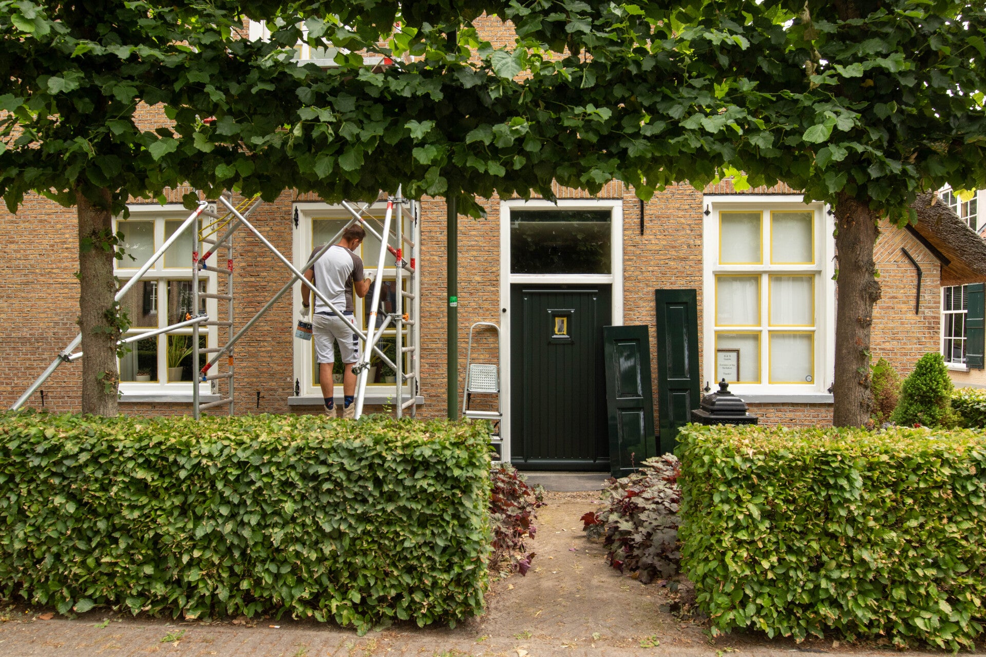 Exterior house painter in action painting the frames of a monumental residence