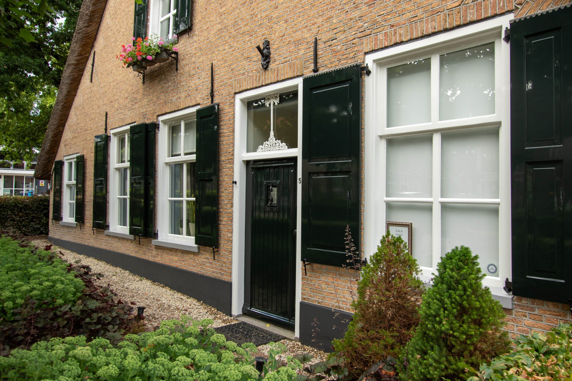 Zijgevel van een monumentale boerderij met pas geschilderde luiken