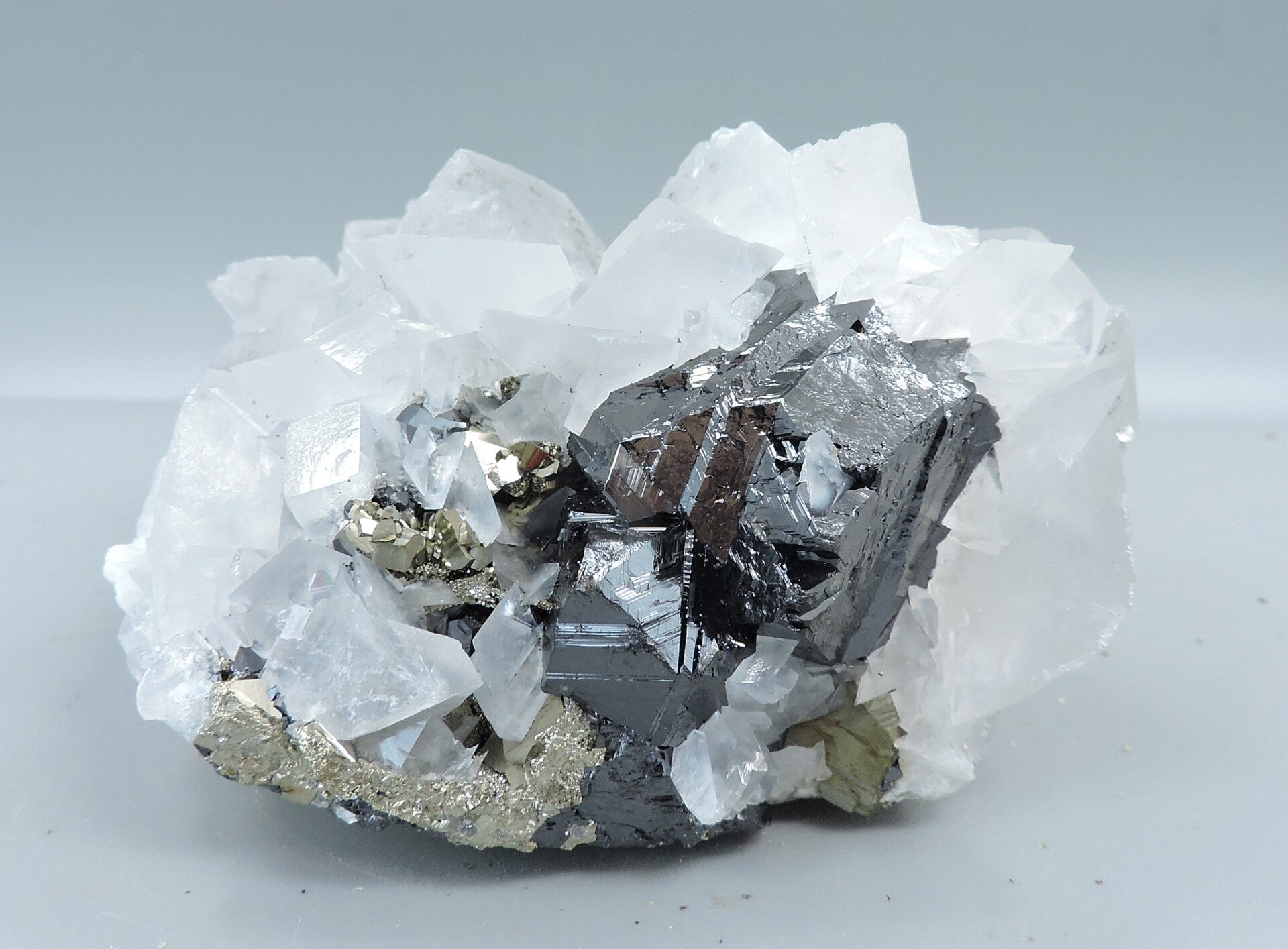 Pink fluorescent calcite (LW) and pyrite on sphalerite from Kosovo – small cabinet size