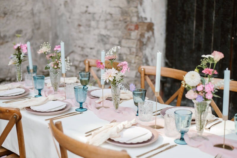 Tafelstyling voor een bruiloft met linnen, kaarsen en bloemwerk in pastelkleuren in de Broerekerk.