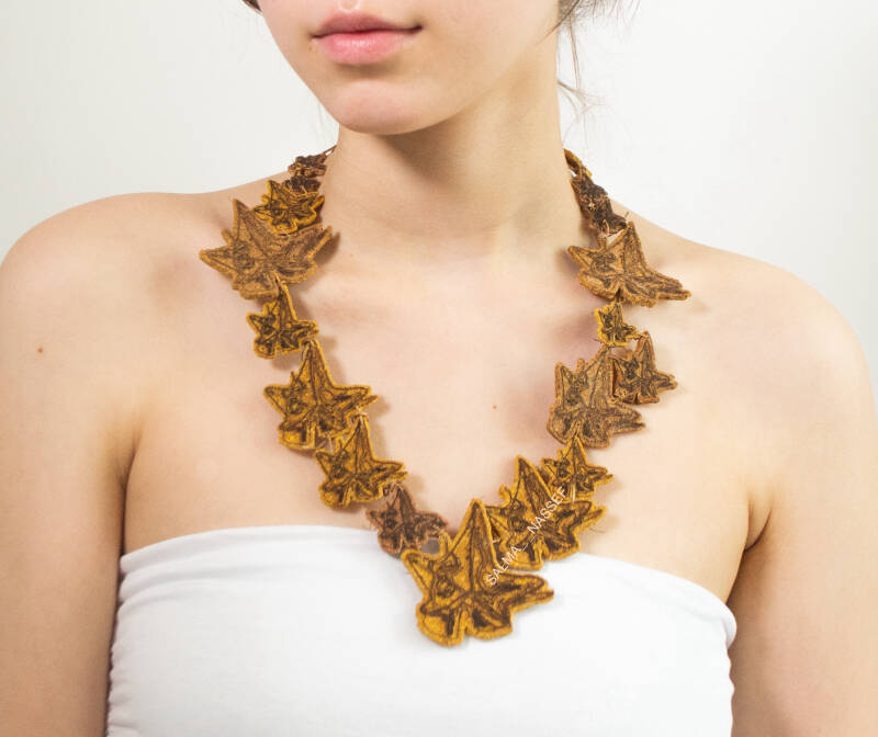 Sustainable handmade necklace with repeated leaf etching worn by model