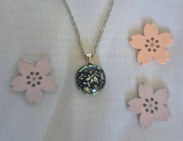 Pendentif en verre dichroique couleur vert et blanc irisé sur un fond noir avec une chaîne en acier inoxydable 45cm.