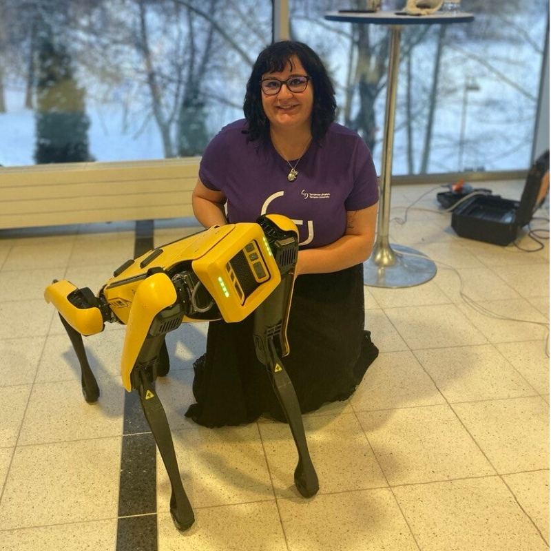 Me sitting on the floor and holding hands with NAO robot, holding COZMO robot on my other hand and infornt of me is CLICKBOT robot. This picture was taken during Co-Desing Workshop with primary school children.