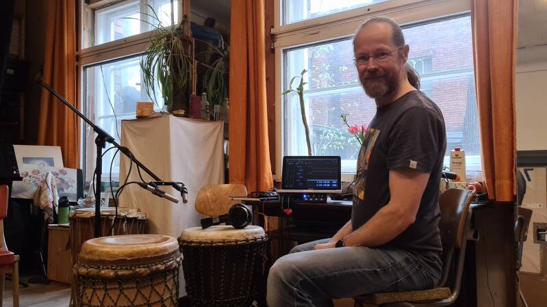 Till Bommer sitzt in seinem Studio mit Aufnahmeequipment und Trommeln