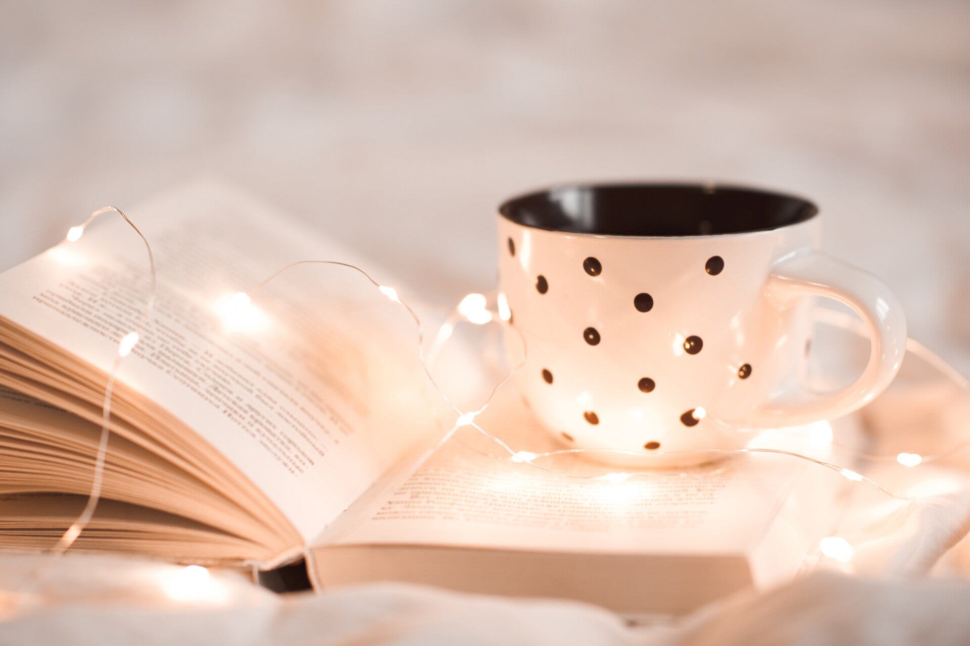 ceramic coffee polka dot mug on top of a book with fairy lights.