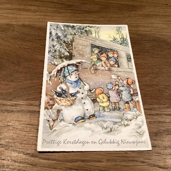 Antieke kerstkaart, kinderen en sneeuwpop bij de trein