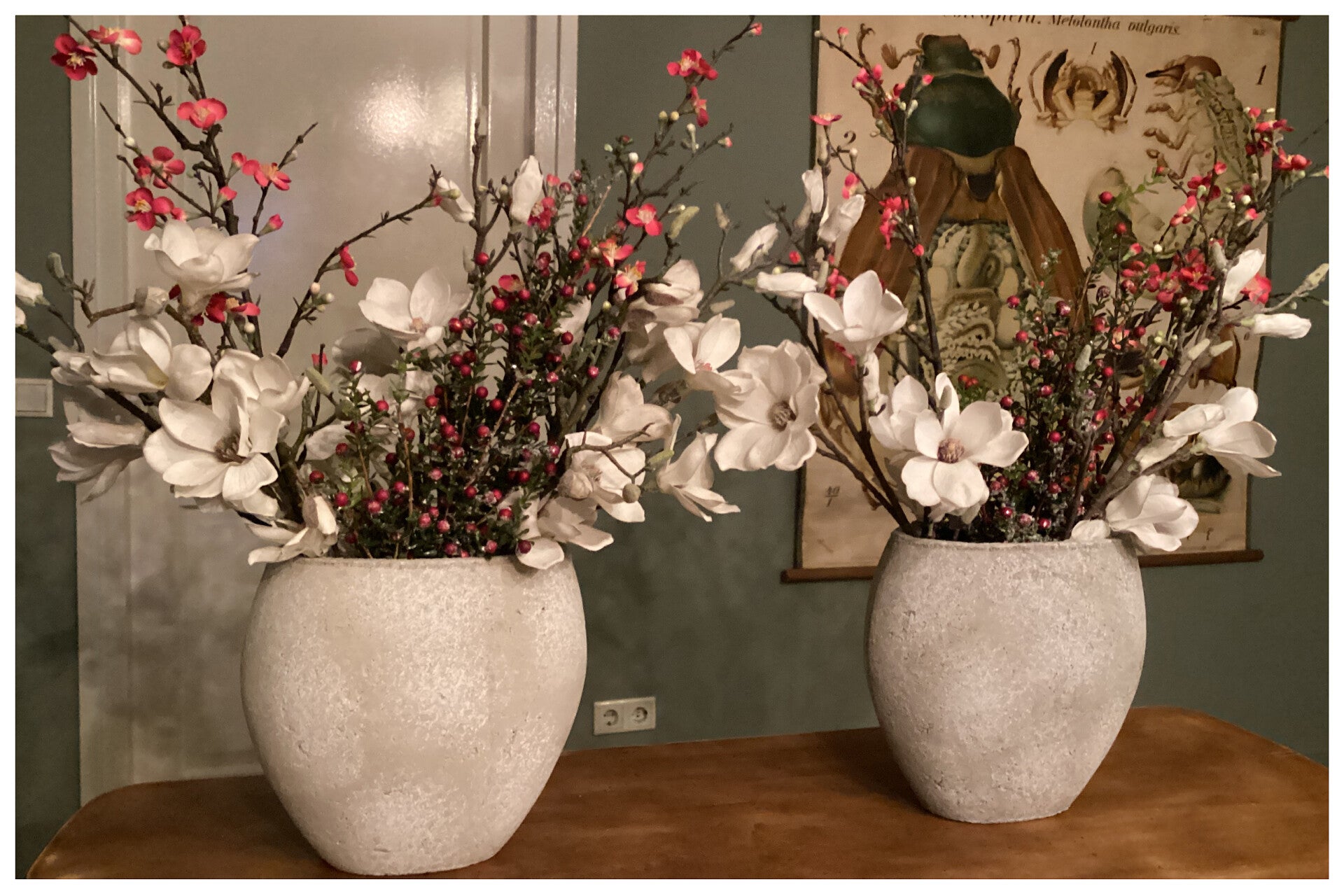 2 betonvazen met magnoliatakken, roze bloesem en berijpte bessentakken