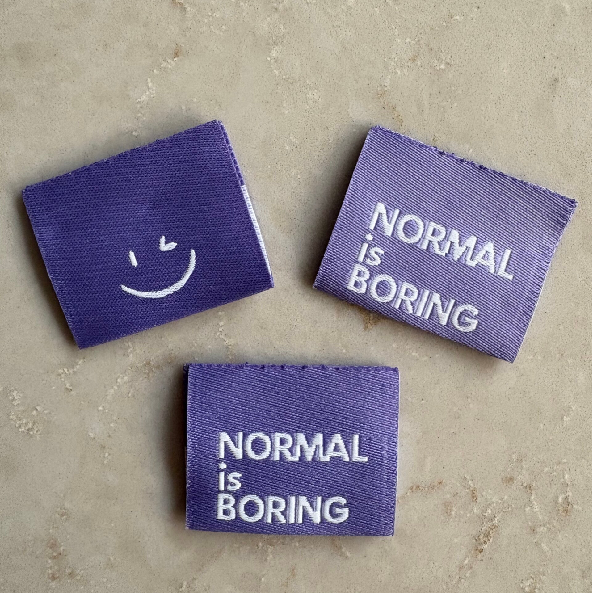Label 'Normal is Boring' - lila
