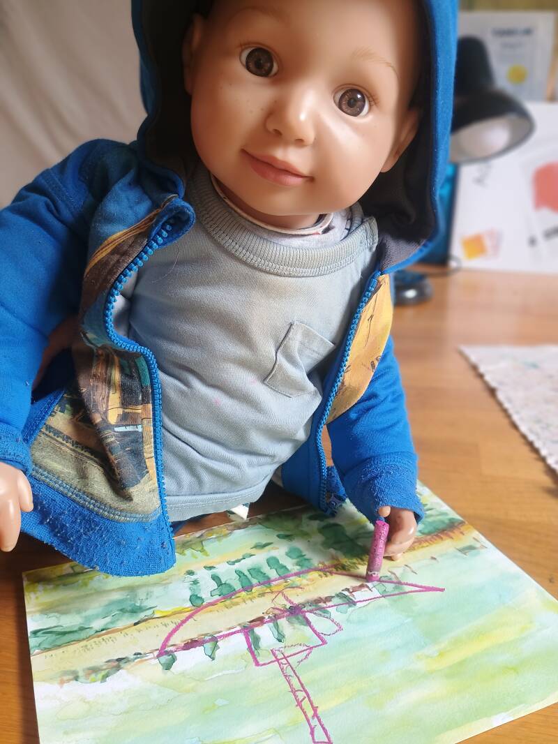 Photo of Alex drawing a boat on one of Jimmy' s landscape drawings 