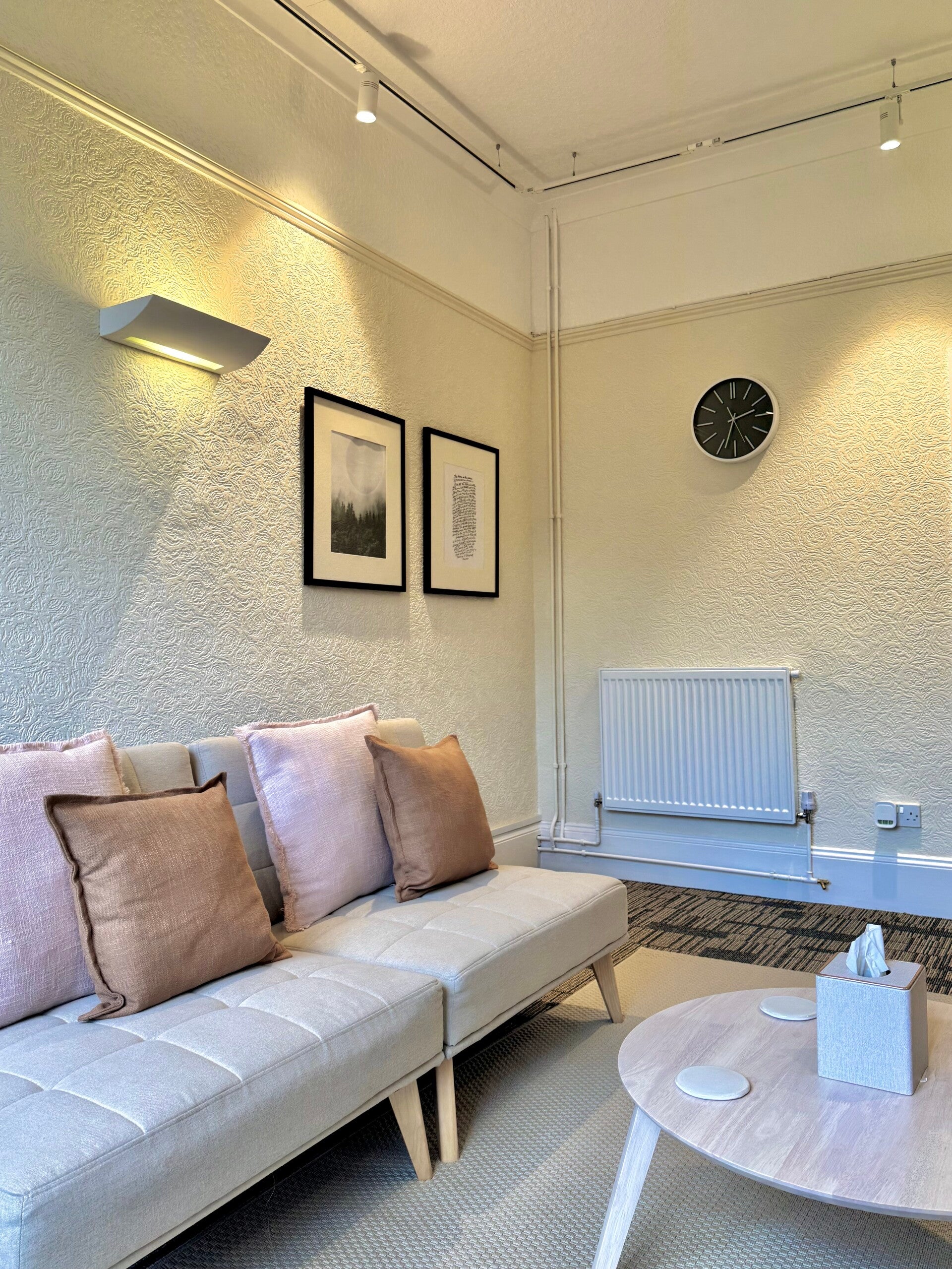 A large comfy sofa with light orange and pale pink cushions