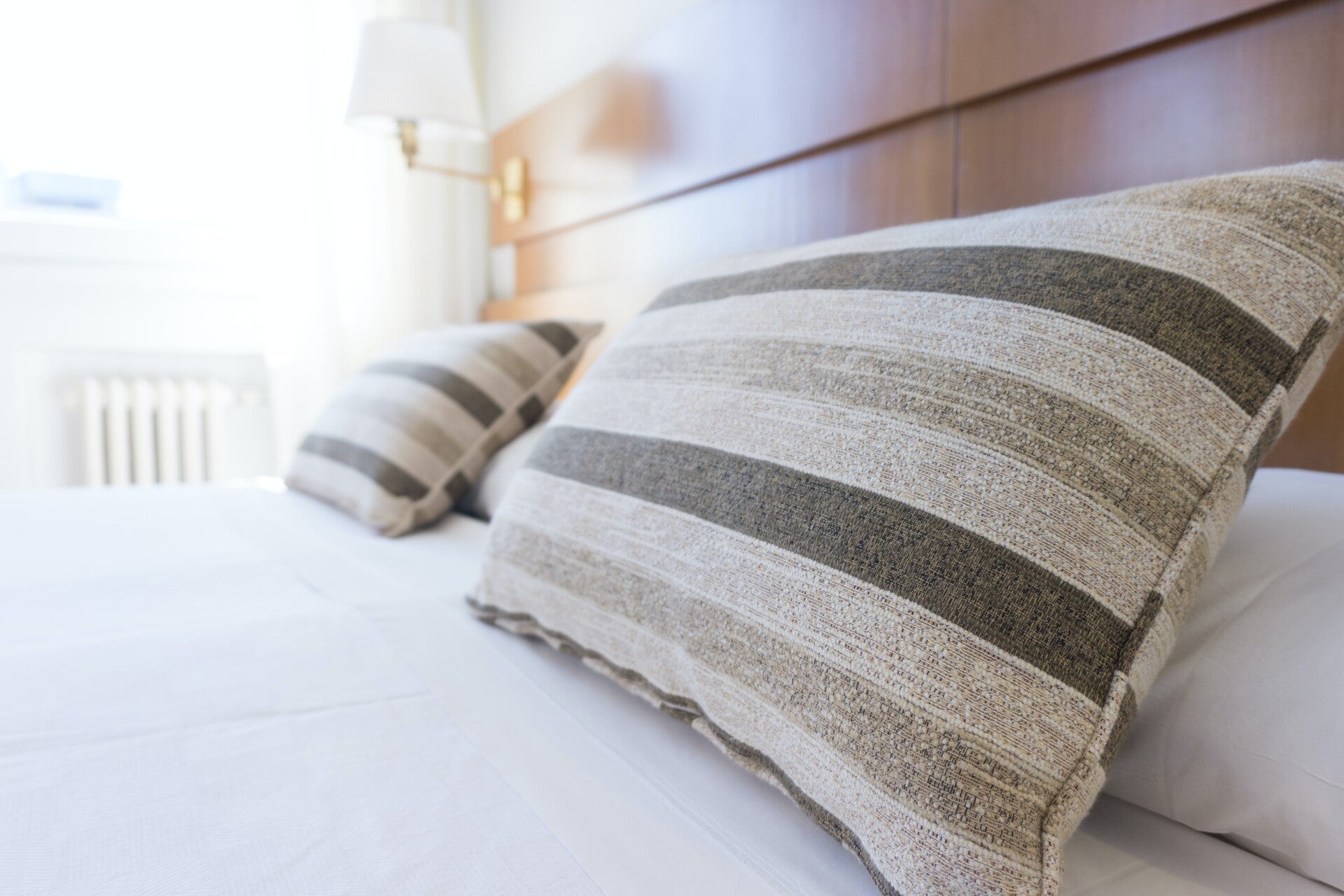 Zoom sur deux coussins personnalisés sur mesure posés sur un lit de suite d'hôtel haut de gamme.
