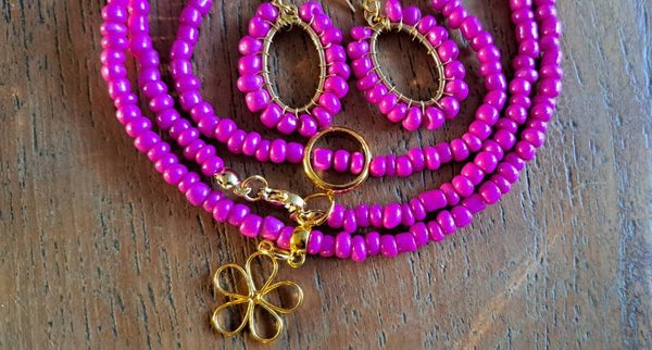Set roze. Ketting met goudkleurige bloem, armband en oorbellen.