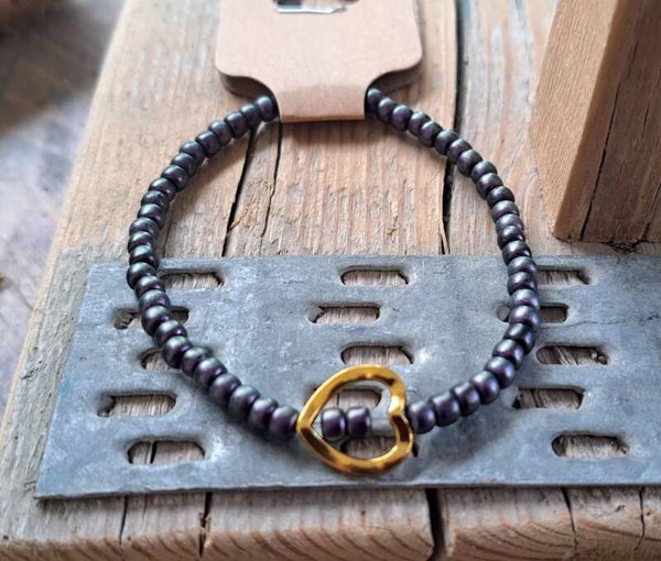 Armband donkerpaars met goudkleurige ring. Elastisch.