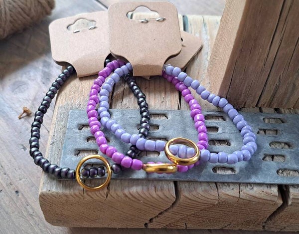Armbanden paarstinten met goudkleurige ring. Elastisch.