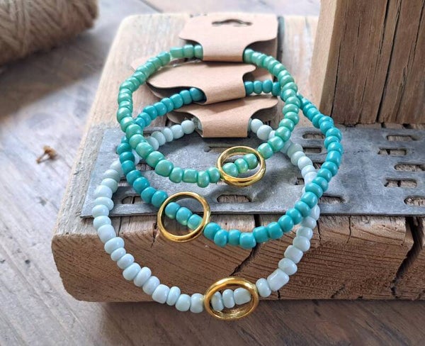 Armbanden groen/blauwtinten met goudkleurige ring. Elastisch.