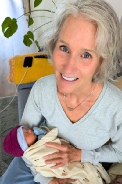 Photo of Maya Frost, founder of Collapse Forward, holding her sixth grandchild as a newborn in 2025.