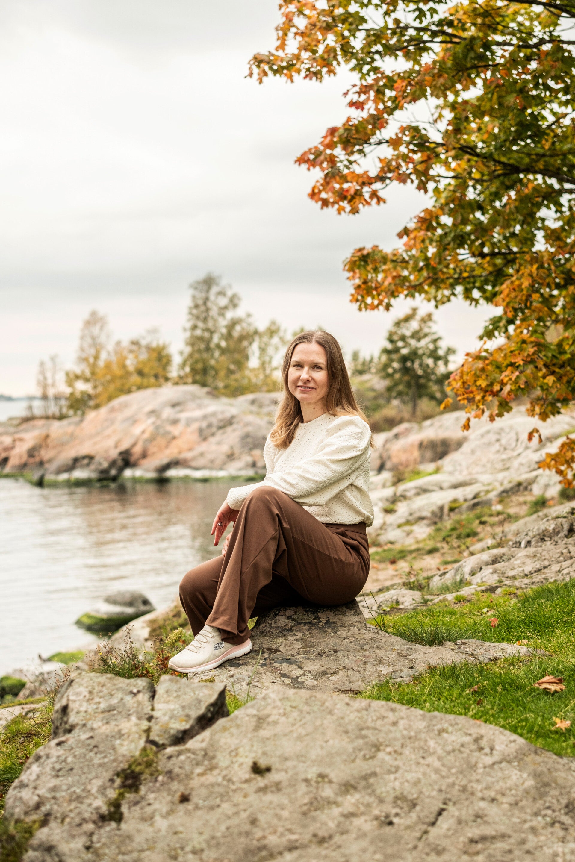 Johanna istuu kalliolla veden ääressä