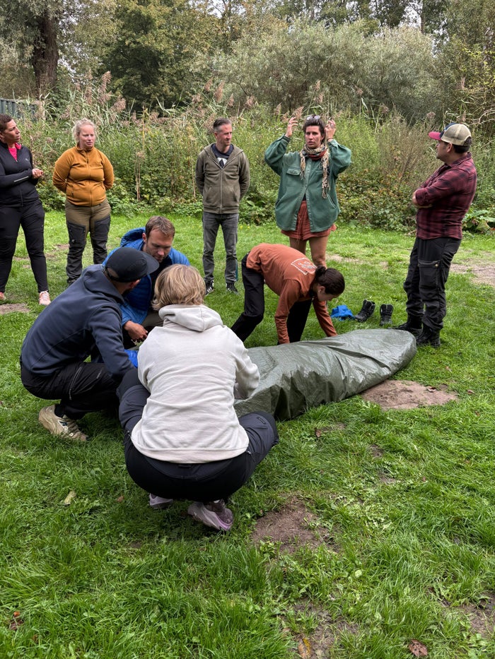 Groep oefent in tweetallen met een slachtoffer tijdens de Wilderness First Aid cursus