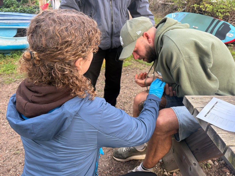Deelnemer verbindt een wond tijdens een praktijkoefening van de EHBO in de wildernis cursus