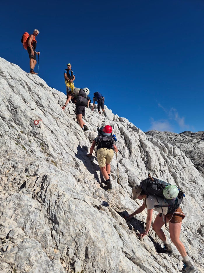 Groep klautert over een rotsplaat op weg naar de Triglav