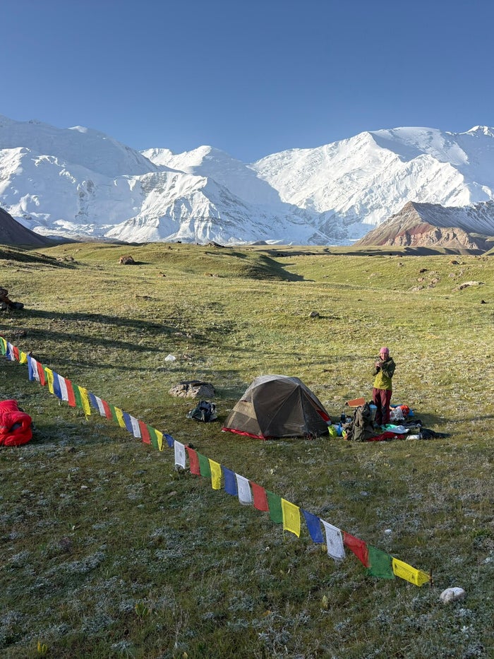 Groene vlakte met tenten en gebedsvlaggen voor Lenin Peak in het Alay-gebergte