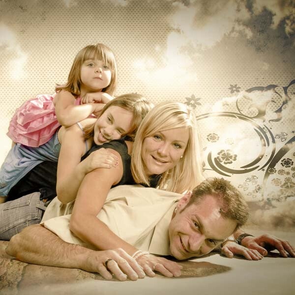 Fröhliches Familienporträt im Fotostudio, bei dem Eltern und Kinder spielerisch übereinander liegen und in die Kamera lächeln.