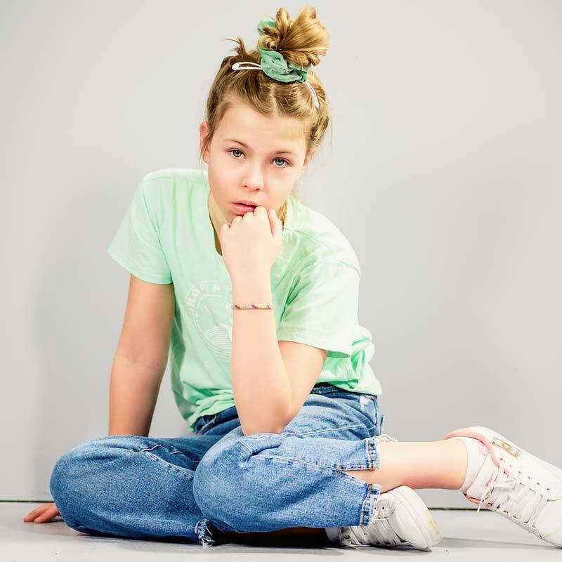 Maedchen mit jeans und gruenem t-shirt posiert stolz vor der kamera