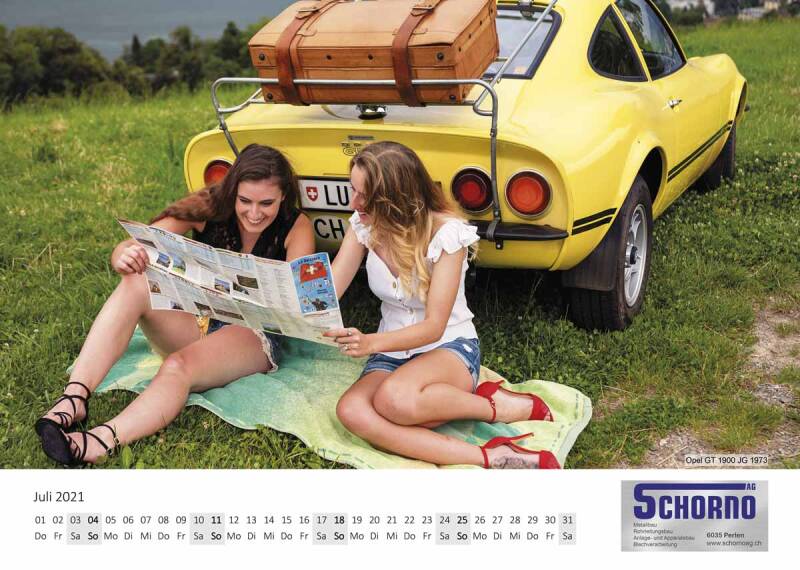 Zwei Frauen sitzen auf einer Wiese vor einem gelben Opel GT 1900 von 1973 und lesen eine Karte