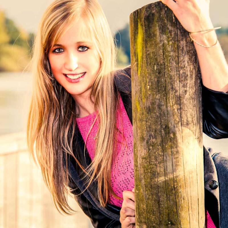 Lächelnde junge Frau mit langen blonden Haaren bei einem Outdoor-Fotoshooting am Vierwaldstättersee in Luzern.