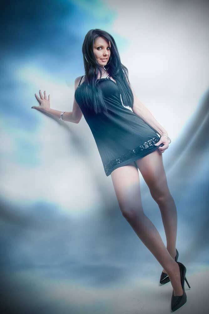 Frau mit schwarzem, langen Haar und kurzem Kleid und lehnt an Studiowand bei einem TFP-Fotoshooting in Emmen nahe Luzern