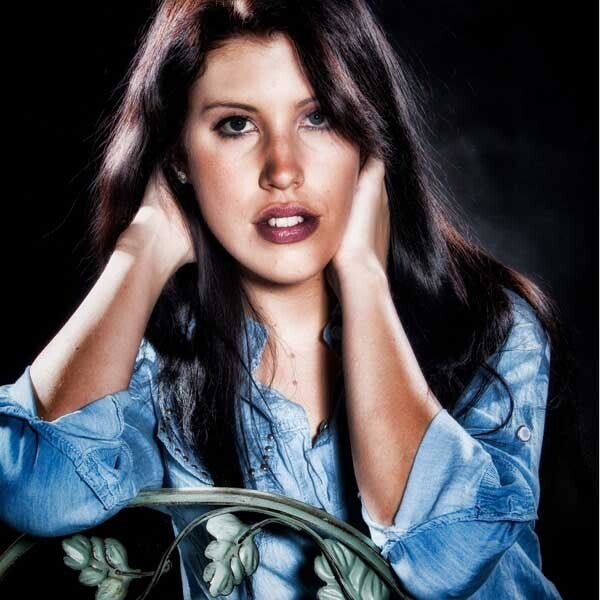 Dunkelhaariges Model im Denim-Hemd stützt den Kopf in die Hände und blickt ernst in die Kamera. TFP-Fotoshooting-Portrait in Luzern.