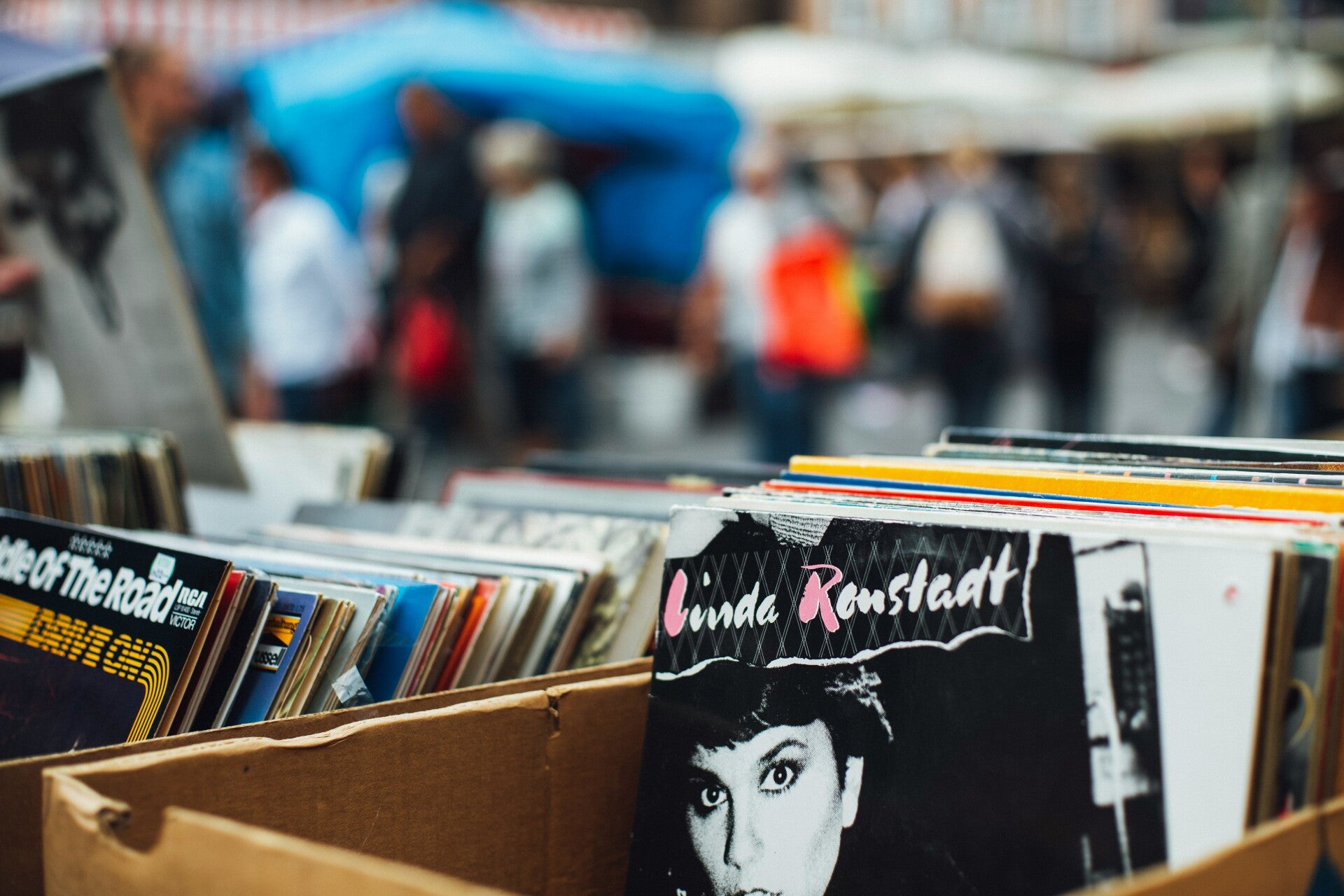 Menschen schlendern über einen großen Flohmarkt mit vielen Ständen, Trödelmarkt in Deutschland, Kultflohmarkt Szene, Bild von Unsplash