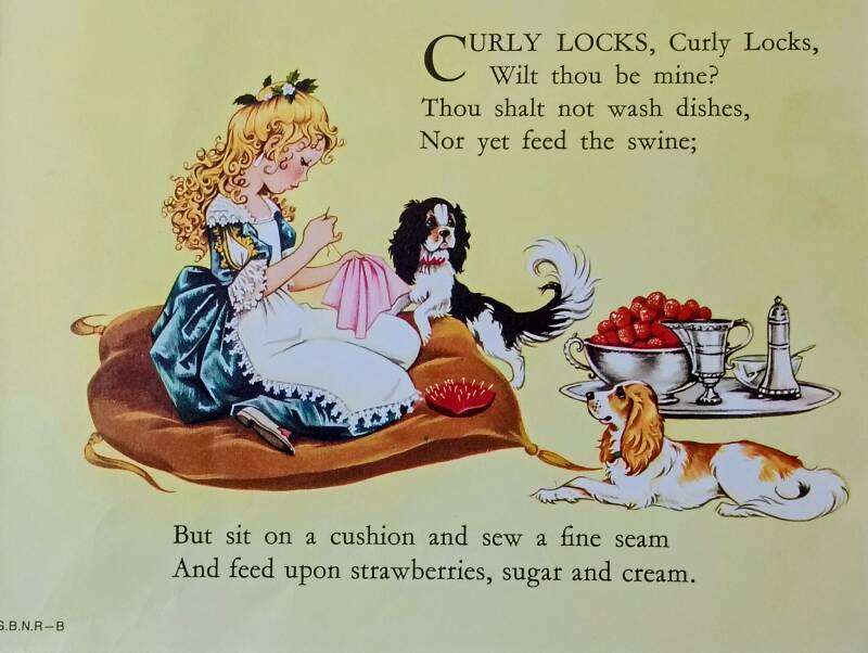 A young girl with long, curly blonde hair, sits on a large cushion sewing. She is accompanied by two toy spaniels, and then is a silver tray bearing a large silver bowl of strawberries, a silver jug and silver sugar sprinkler