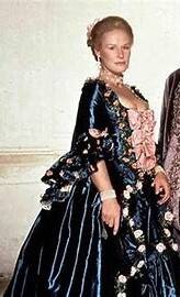 Photo of a woman with fair hair wearing a dark satin 18th Century gown, trimmed with pink rosebuds