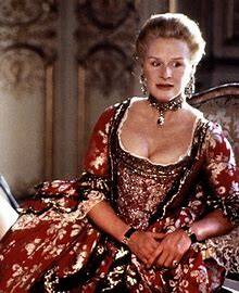 Photo of a seated woman with fair hair, wearing a dark red brocade 18th Century gown. She also wears an ornate choker around her neck