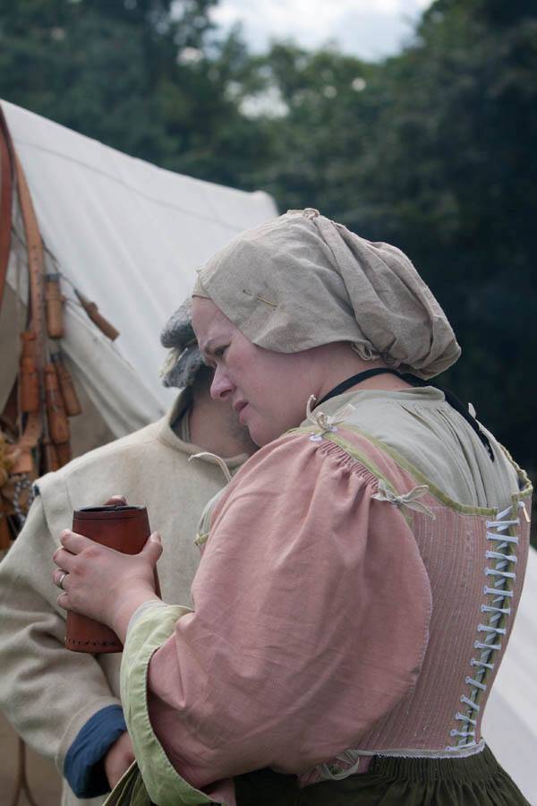 Woman wearing 17th Century clothing and holding a brown leather tankard