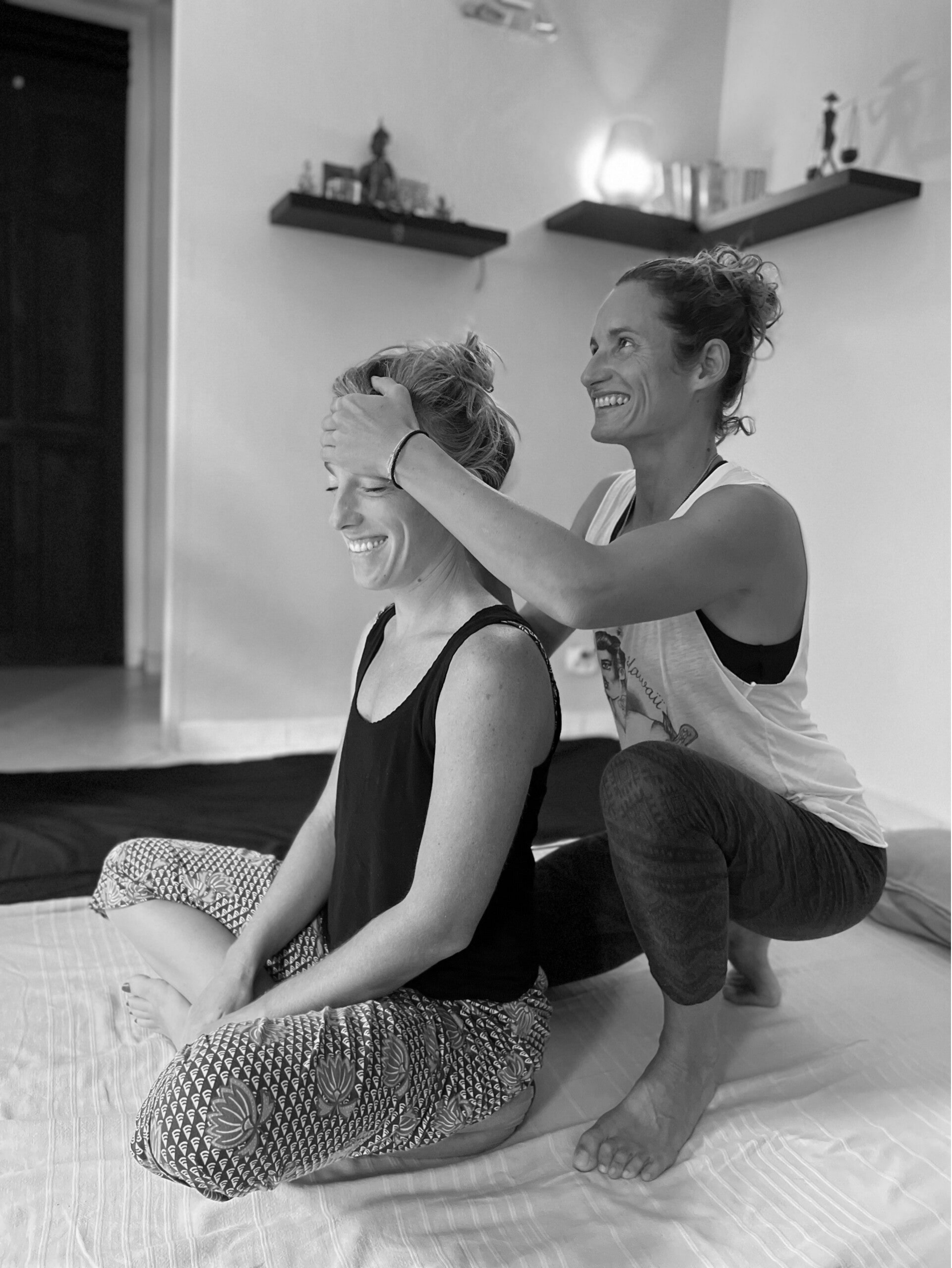 Praticienne enseignant une technique du massage thaïlandais Nuad Bo Rarn, démonstration d’un geste précis sur le front d’une élève en posture assise lors d’une formation professionnelle.