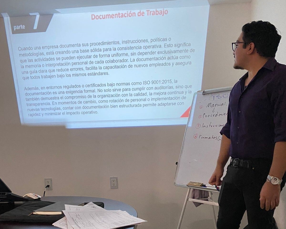 Instructor experto impartiendo curso de capacitación normativa y formación de auditores a grupo de profesionales en sala de entrenamiento.