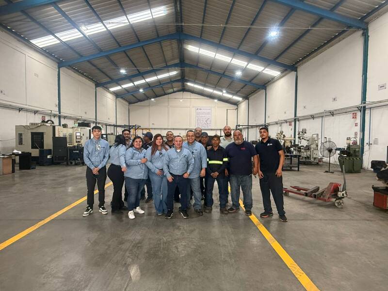 Equipo de consultoría y personal operativo en piso de producción de industria metalmecánica tras jornada de asesoría técnica.