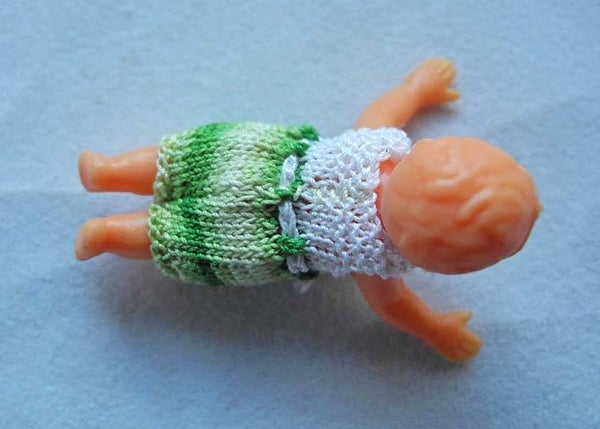 Plastic popje, buikligging, groen en wit pakje - Plastic doll laying on its belly, green and white suit