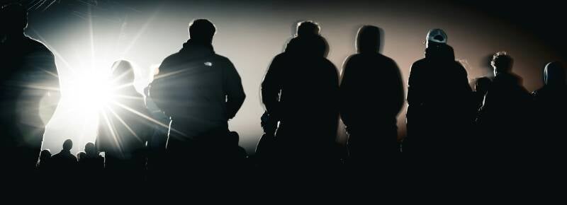   Audience silhouettes backlit by stage lighting during a professionally produced live event.