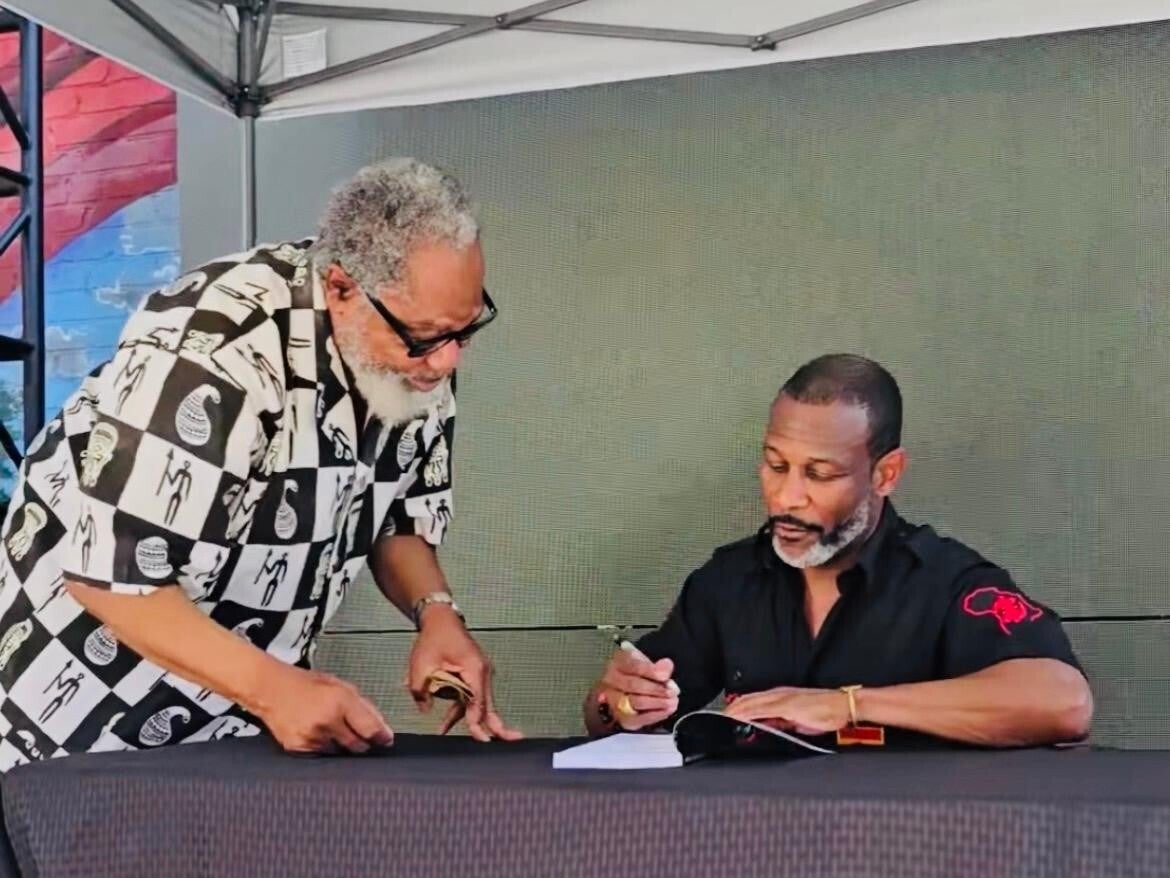 sundiata-signing-a-book-for-a-customer-standard-ncxnwp.jpg