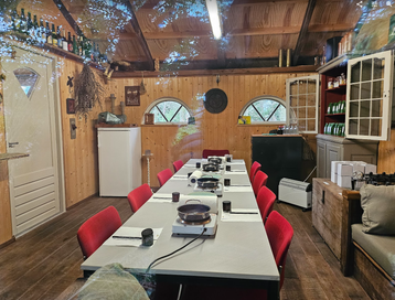 Deelnemers aan tafel tijdens een kruidenworkshop in een warme houten ruimte, bezig met het maken van natuurlijke zelfzorgproducten zoals zalven en oliën